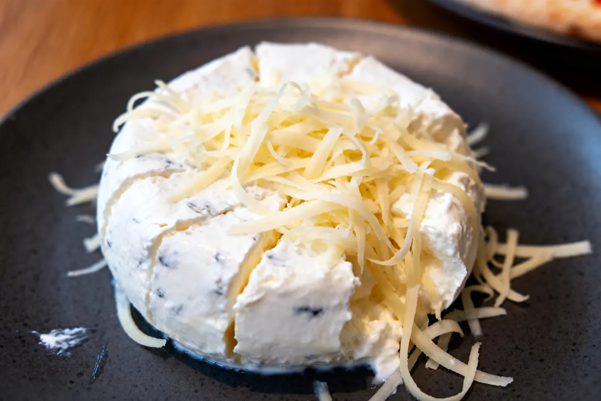 Fromage stracciatella crémeux garni de copeaux sur une assiette noire élégante