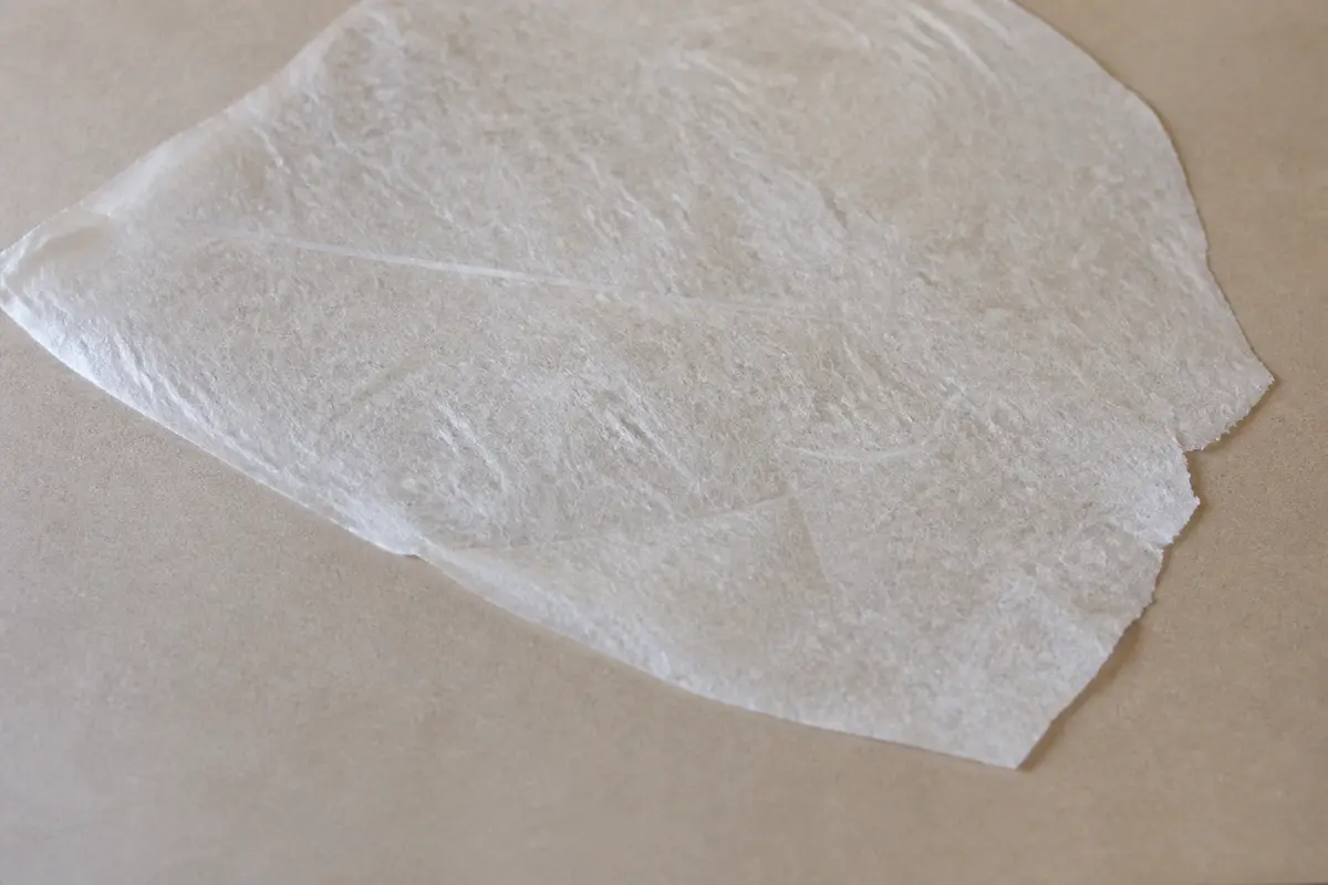 Feuille translucide de papier de riz posée sur une surface beige