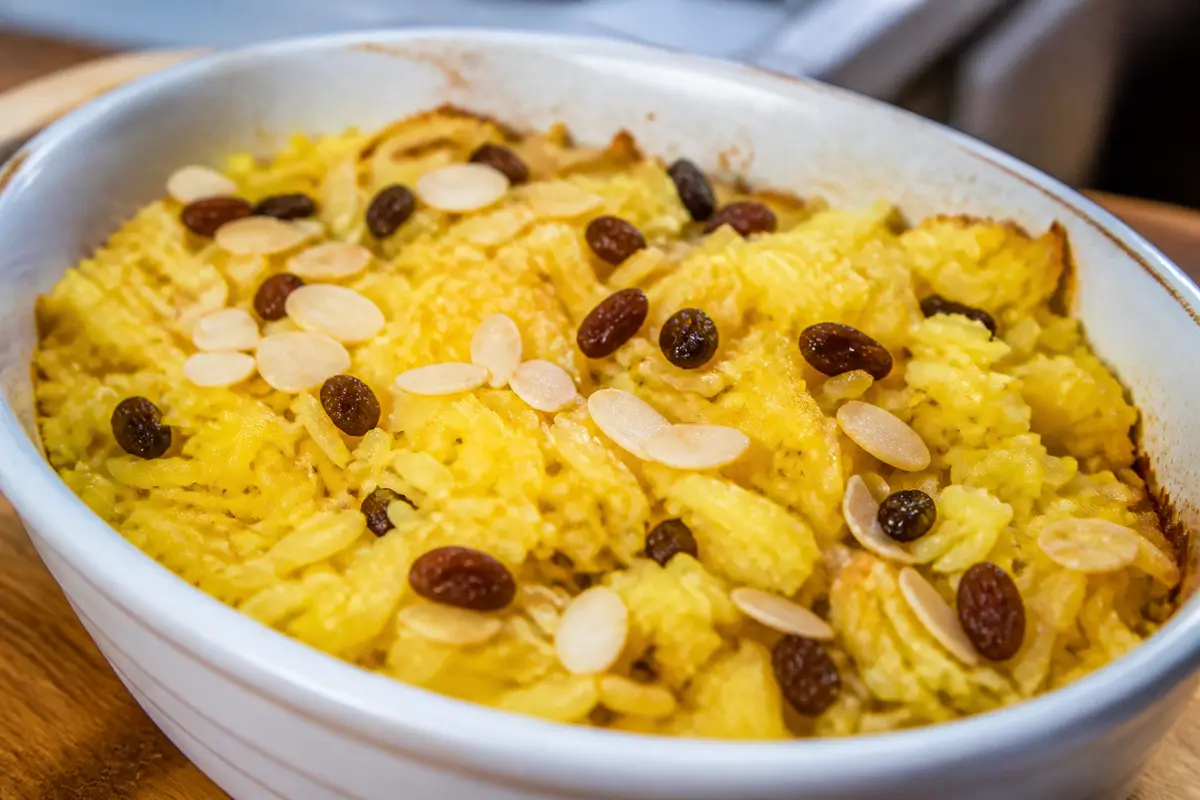 Plat de riz madras safrané garni d'amandes et raisins dans un plat blanc ovale